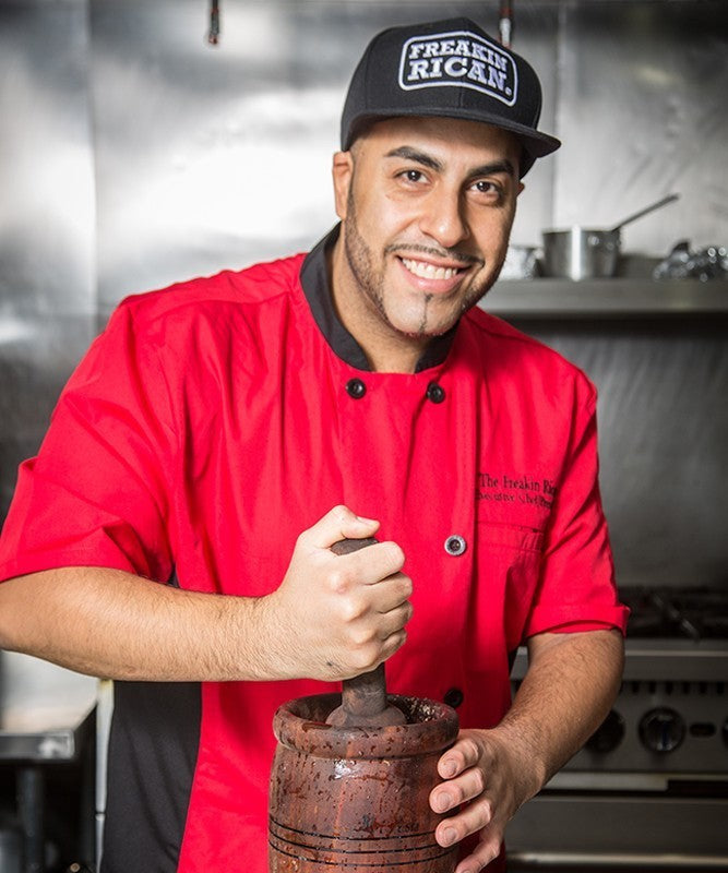 Derick Lopez, The Freakin Rican, using a wooden pilón in his restaurant kitchen
